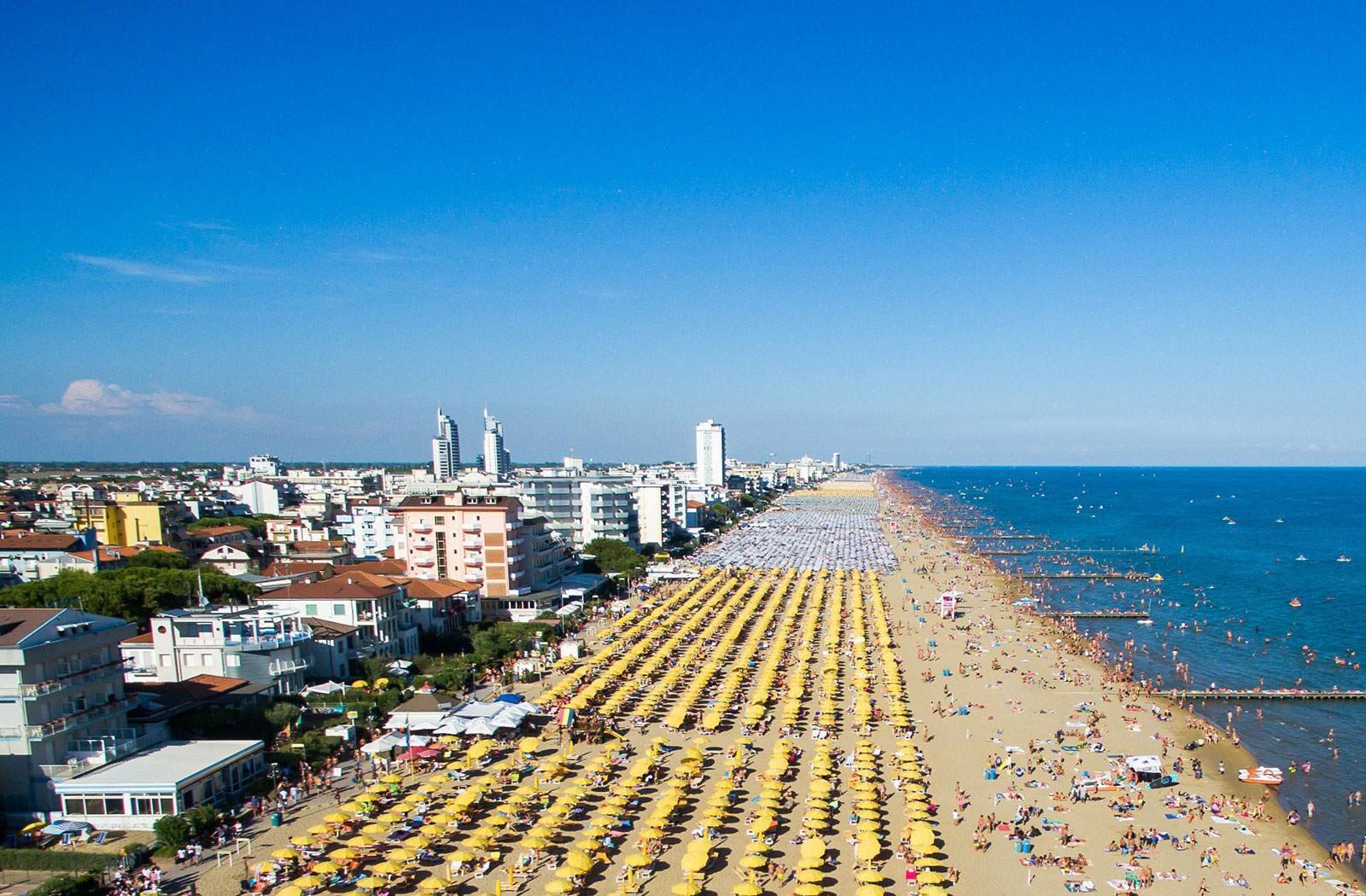 Lungomare di Jesolo all'alba con palme e cabine sulla spiaggia